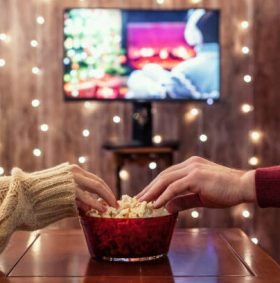 Christmas eve. Couple watching tv and eating popcorn. Home cinema. Cropped, close up